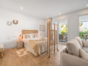 A bedroom with a bed, bedside table, lamp, and a view of the outside. - Stylish 2-pax Stay in Alcazaba Lagoon (Casares)