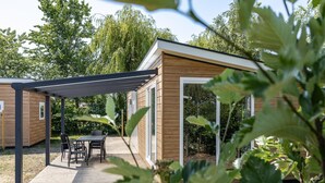 A wooden cabin with a covered patio and a table with chairs. - Cosy Family Chalet With Covered Terrace (Burgh-Haamstede)