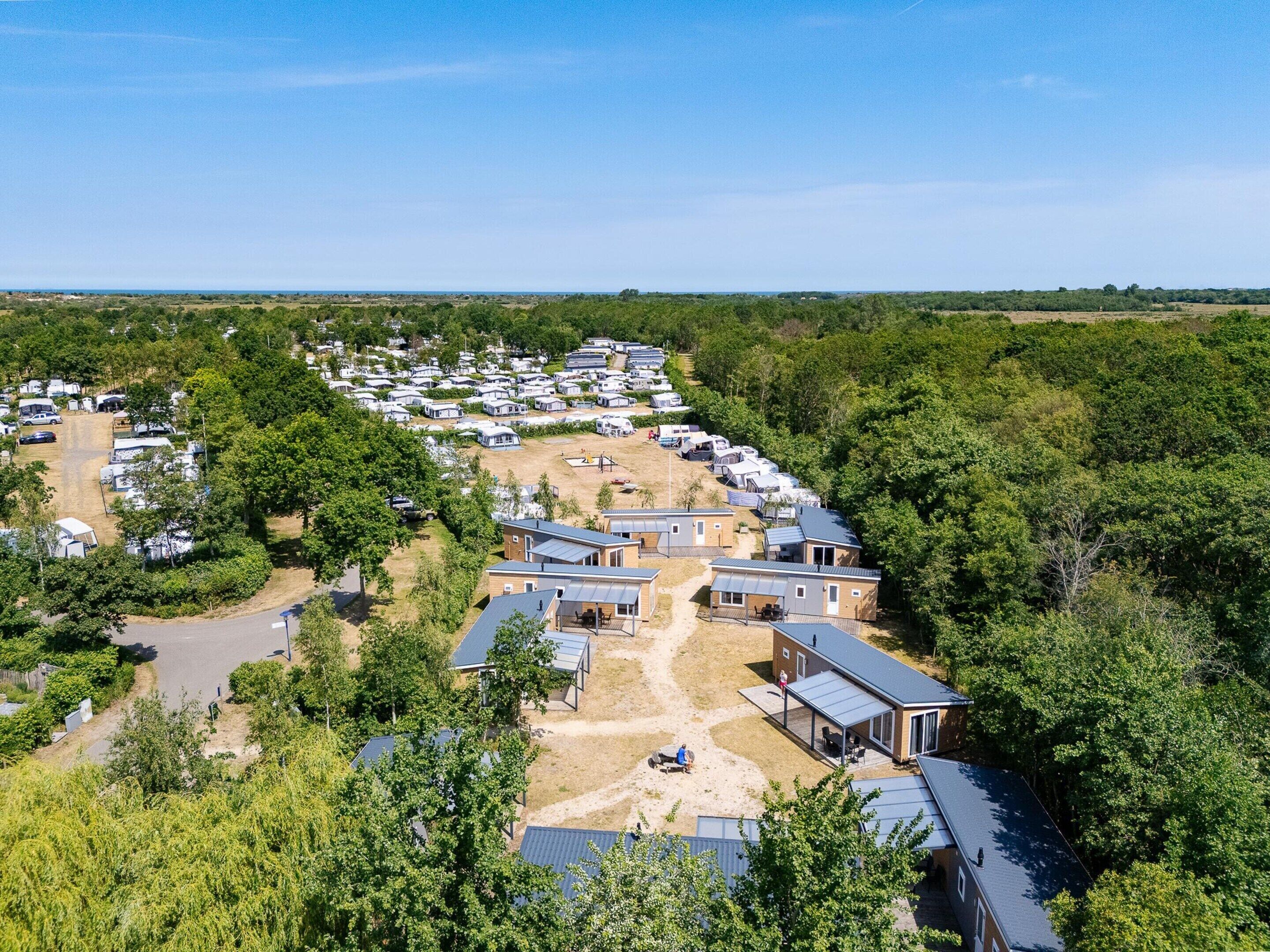 Un parc de caravanes comprenant de nombreuses caravanes et des mobil-homes, entouré d’arbres et bordé de terrains ouverts.