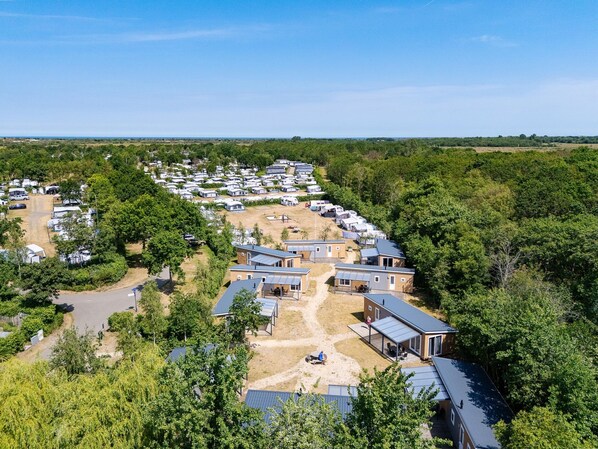 A caravan park with multiple caravans and mobile homes, surrounded by trees and open land. - Cosy Family Chalet With Covered Terrace (Burgh-Haamstede)