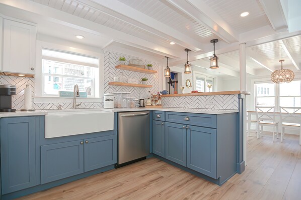A modern kitchen with blue cabinets, a dishwasher, and a herringbone-patterned backsplash.