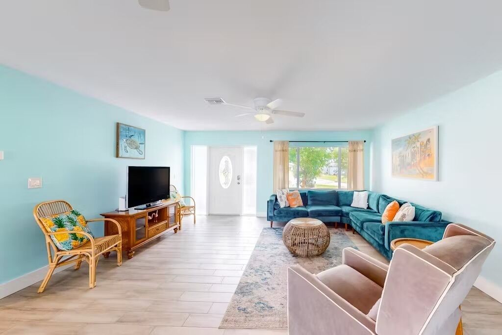 A living room with a TV, sofa, and chairs.