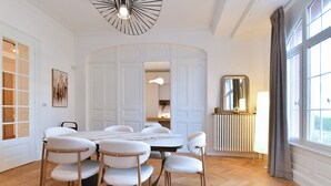 Un coin repas avec une table ronde et six chaises, un grand miroir et une fenêtre avec des rideaux.