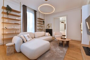 A modern living room with a sectional sofa, wooden shelving units, a round coffee table, and a flat-screen TV. - Large, chic and cosy apartment - Colmar (Colmar)