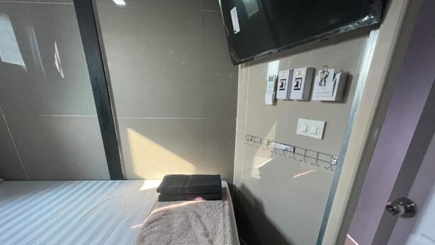 A hotel room with a bed, a towel, a TV mounted on the wall, and a control panel with various buttons. - Charinsup Pinklao hotel (Bang Kruai)