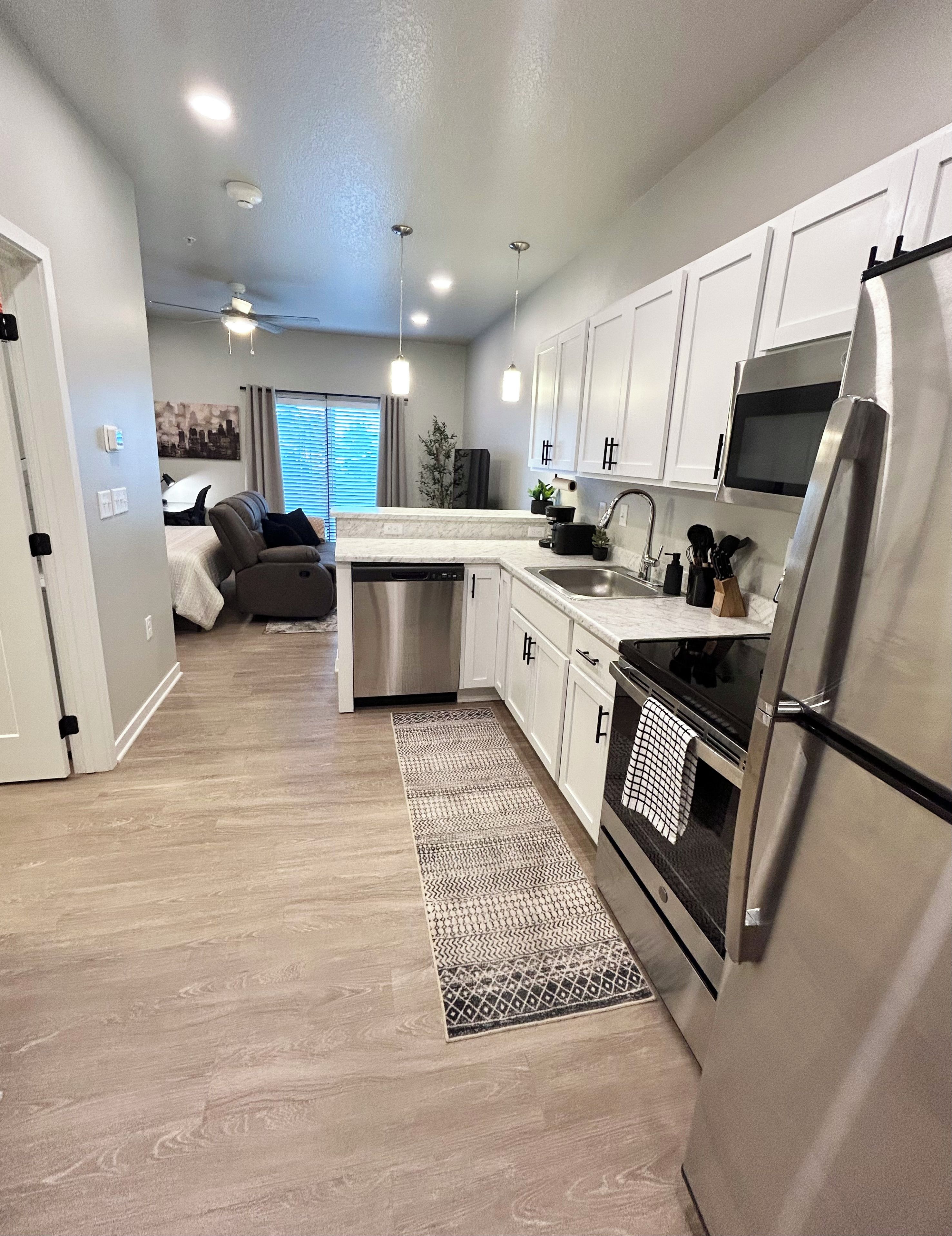 A modern kitchen with white cabinets, stainless steel appliances, and a central island.