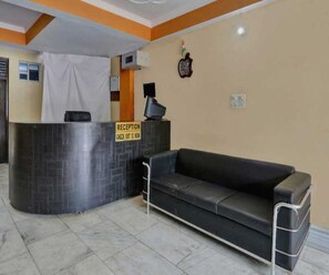 A reception area with a check-out counter, a black leather couch, and a tiled floor.