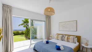 Une chambre avec un grand lit, une vue sur un jardin et un balcon.