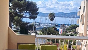A terrace with a table and chairs, overlooking a marina with boats and a mountainous backdrop. - Well-located apartment with beautiful sea view. (Saint-Raphaël)