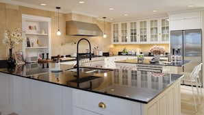 A modern kitchen with white cabinetry, a large island with a black countertop, stainless steel appliances, and recessed ceiling lighting. - The Ridge: A Secluded Luxury Estate with Pool (Santa Fe)