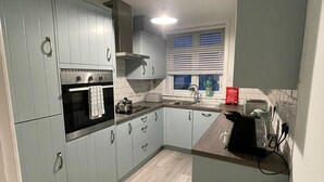 A compact kitchen with light blue cabinets, a built-in oven, a sink, and a small trash bin. - Cosy 2 bed retreat 10 mins to airport/beach/city ctr!  5 mins to train station (Bournemouth)
