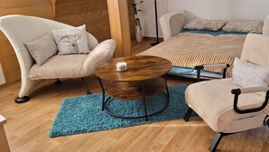 Una sala de estar acogedora con un sofá, dos sillones, una mesita de centro y un tapete azul.