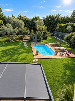 A backyard with a swimming pool, a small shed, and a patio area with chairs and umbrellas. - AIR-CONDITIONED PROVENCAL VILLA WITH A POOL AND SPA ON THE WAY TO BIOT   (Antibes)