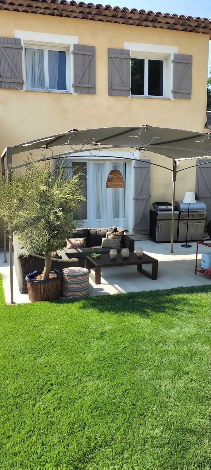 A covered outdoor seating area with a table, chairs, and a grill.