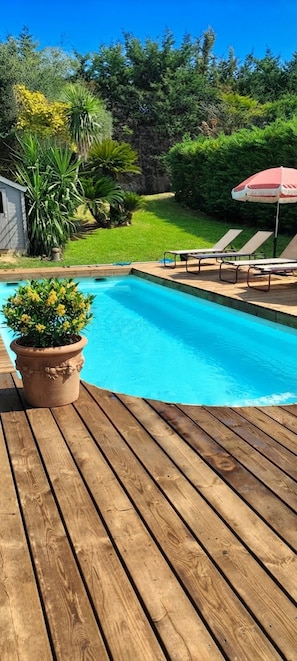 A wooden deck with a swimming pool, surrounded by greenery and a small shed. - AIR-CONDITIONED PROVENCAL HOUSE WITH POOL AND SPA ON THE ROAD TO BIOT (Antibes)