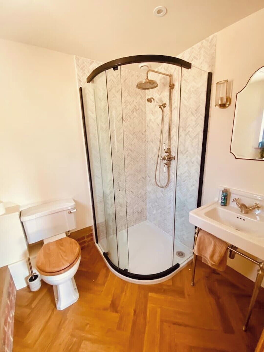 A modern bathroom with a glass-enclosed shower, a toilet, and a sink.