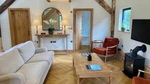 Een gezellige woonkamer met een bank, een salontafel, een rode fauteuil, een open haard en een televisie.