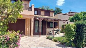 Un immeuble résidentiel doté d’un patio couvert, d’une porte et d’un petit espace jardin.