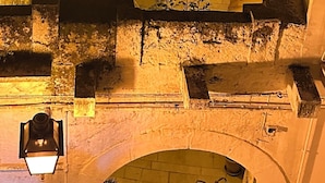 A narrow alleyway with a stone archway, a staircase with a metal railing, and a small balcony with a potted plant. - La Casa dell' Arco Nr 45/47 Entire house in historic center (Triggiano)
