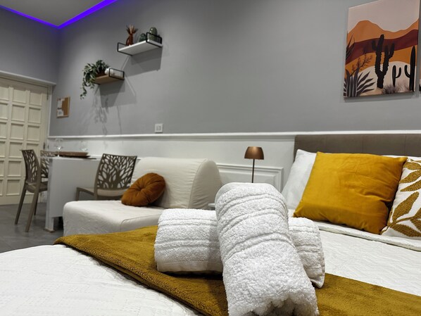 A neatly arranged hotel room with a bed, a dining area, and a painting on the wall.