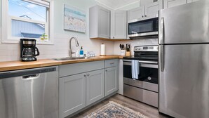 A modern kitchen with stainless steel appliances, grey cabinets, and a wooden countertop. - Coral Cottage Unit #1: Walk to Beach, Pet Friendly (Rockaway Beach)