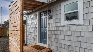 Una casa con revestimiento de tejas grises, una puerta principal azul oscuro y un letrero de madera con el número 413.