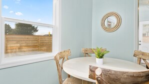 Un comedor con una mesa redonda, sillas de madera, una planta en maceta y un espejo en la pared.