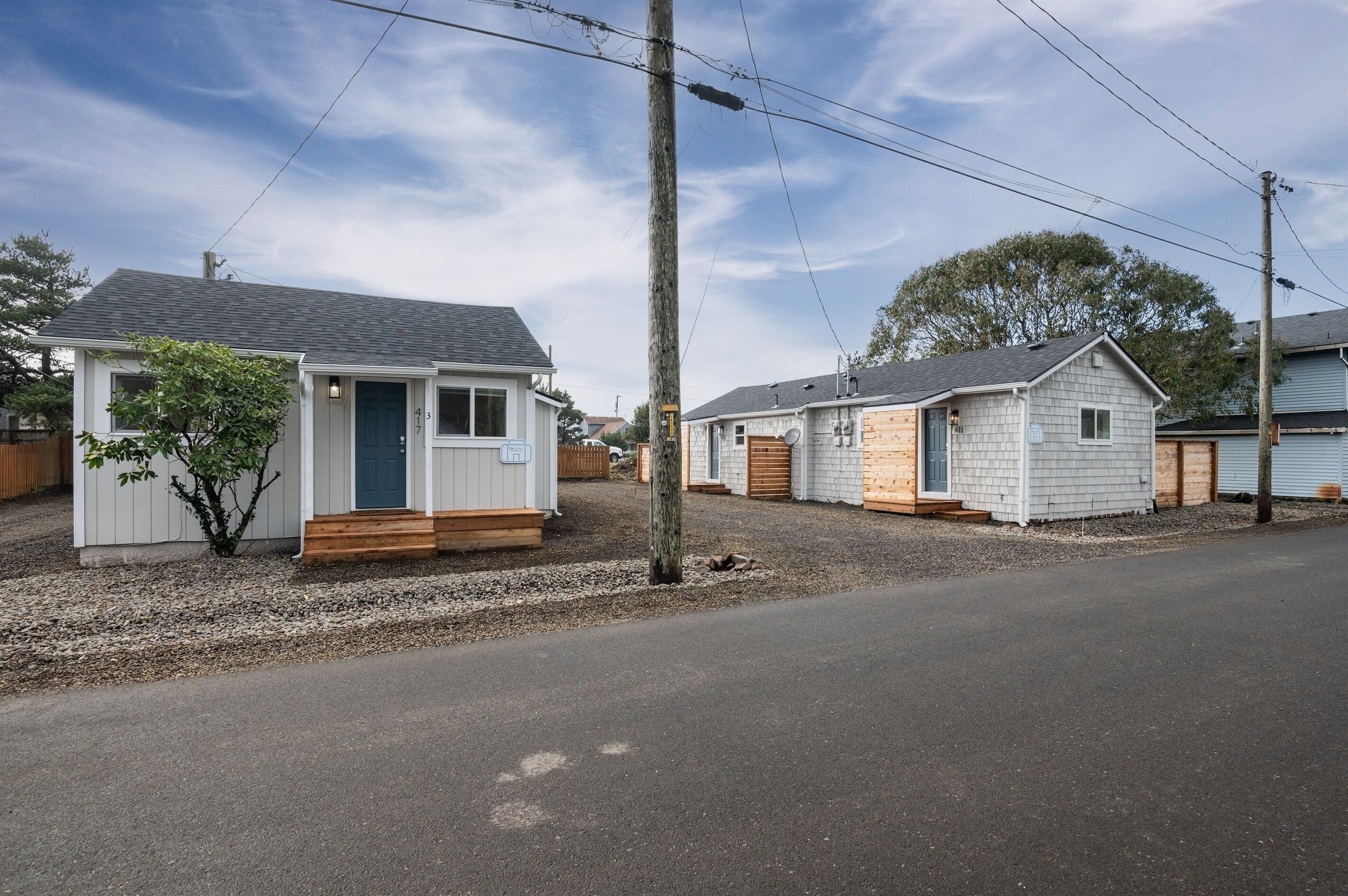 Une rangée de petites maisons à un seul étage, avec une allée en gravier et un ciel dégagé.