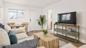 Ein Wohnzimmer mit Sofa, Couchtisch, Fernseher und einem Essbereich mit Tisch und Stühlen.