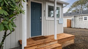 Ein Haus mit blauer Tür, Holzstufen und einer kleinen Veranda.