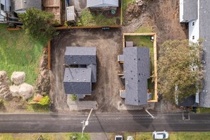Vista aérea de una zona residencial con dos casas, una calle y un pequeño aparcamiento.