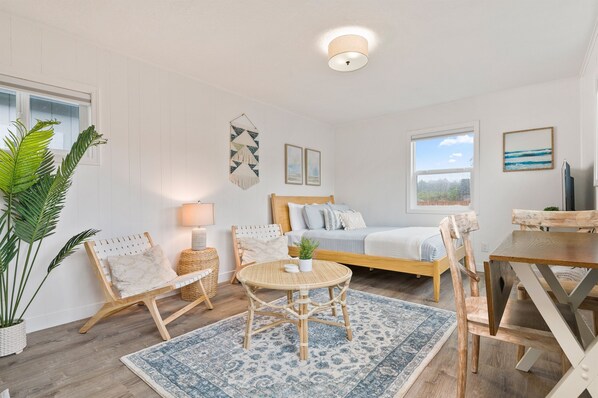 Un dormitorio acogedor con cama, mesitas de noche, una mesa redonda y una silla.