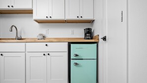 A kitchen with white cabinets, a wooden countertop, a sink, a coffee maker, and a teal refrigerator. - Inn at Rockaway Beach #1: Walk to Beach, Pets OK (Rockaway Beach)