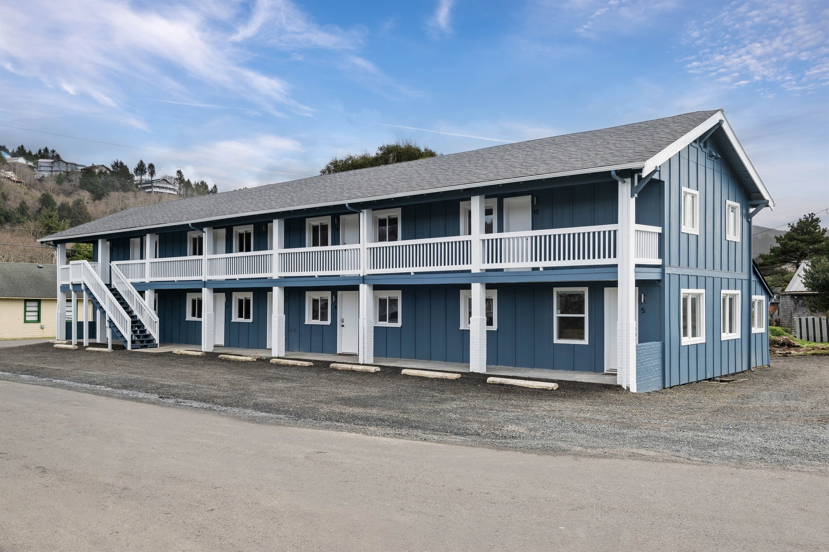 A two-story motel with a balcony on the second floor, a covered front porch, and a staircase leading to the upper level.