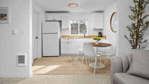 Una cocina moderna con armarios blancos, encimera de madera y una zona de comedor con mesa y sillas.