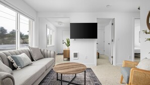 Ein modernes Wohnzimmer mit einer Couch, einem Couchtisch und einem an der Wand montierten Flachbildfernseher.