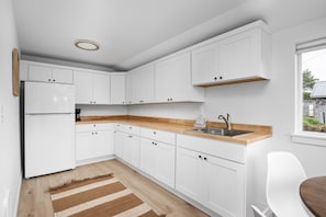 Eine moderne Küche mit weißen Schränken, einer Holz Arbeitsplatte und einer eingebauten Spüle.