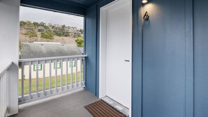 A blue exterior wall with a white door and a small balcony with a white railing. - Inn at Rockaway Beach #6: Walk to Beach, Pets OK (Rockaway Beach)