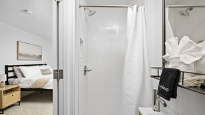 Un baño moderno con mampara de vidrio, una bañera blanca y un lavamanos con toallero.