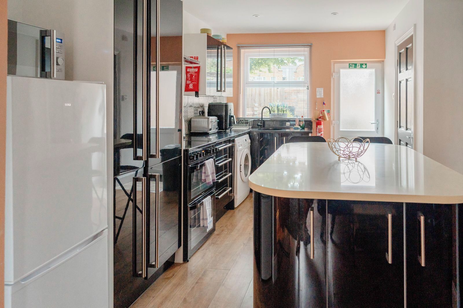 A modern kitchen with a central island, stainless steel appliances, and a view to the outside.