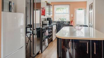 A modern kitchen with a central island, stainless steel appliances, and a view to the outside.