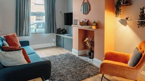 A living room with a sofa, armchair, and a small table with a lamp.