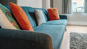 A blue sofa with multiple cushions in a living room. - Cosy Home From Home | Walk to Centre | Free Parking (York)
