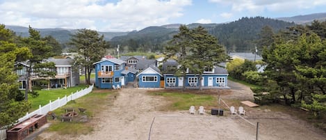 Et boligområde med flere huse, en sandfyldt gårdhave og et hvidt stakittet hegn.