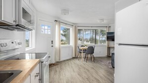 Cozinha moderna com armários brancos, bancada de madeira e área de refeições com mesa e cadeiras.
