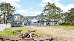 Une rangée de maisons bleues, avec un foyer et des bancs au premier plan.