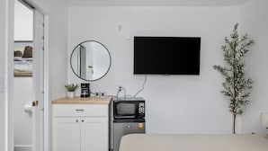 Une chambre d’hôtel moderne équipée d’un lit, d’un téléviseur à écran plat, d’un four à micro-ondes, d’une petite machine à café, d’une plante en pot et offrant une vue sur l’extérieur.