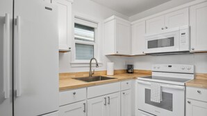 Een moderne keuken met witte kasten, een roestvrijstalen spoelbak, een magnetron en een oven.