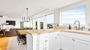 Une cuisine moderne avec des armoires blanches, un plan de travail en bois et une grande fenêtre donnant sur l’extérieur.