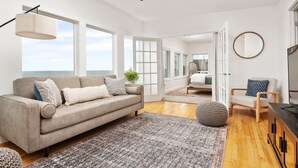 Un salon moderne avec un canapé, un miroir rond et un ventilateur de plafond.